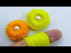 two crocheted buttons are being held by a person's finger