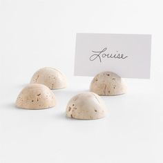 four small white rocks sitting next to a sign with the word louise written on it