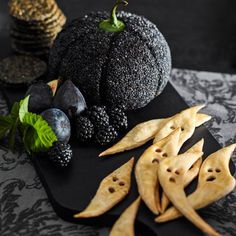 an assortment of fruits and crackers on a black platter next to each other