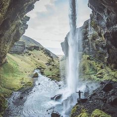 an image of a waterfall coming out of the side of a cave with moss growing on it