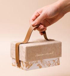 a person is holding a brown and white box