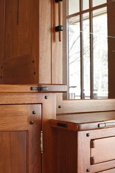 a wooden cabinet with two drawers and a mirror in the back ground near a window