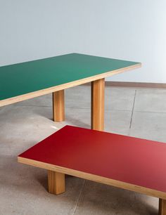 two wooden benches sitting next to each other on top of cement floored ground in front of a wall