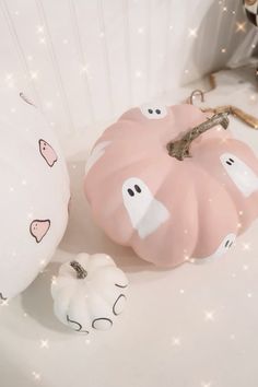 two white pumpkins sitting on top of a table next to each other with ghost faces painted on them