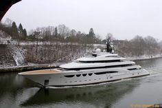 a large white boat traveling down a river next to a shore covered in snow and trees