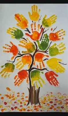 a tree made out of handprints on a white paper with orange, yellow and green leaves