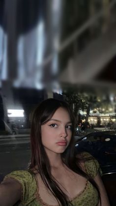 a woman standing in front of a building at night with her hand on her hip