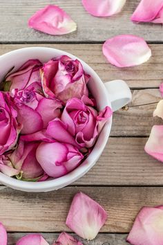 a white cup filled with pink roses on top of a wooden table and the words dying rose petals try this simple 2 minute method