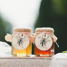 two jars of honey sitting on top of a table