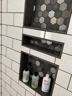 two shelves with soaps and lotion bottles on them in a tiled bathroom stall