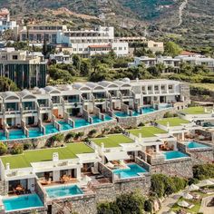 an aerial view of the resort with swimming pools and mountains in the background, surrounded by lush greenery