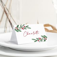 a white plate with a place card on it and some red berries around the edge