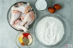 ingredients to make chicken wings laid out in bowls on a gray surface with oranges, eggs and flour