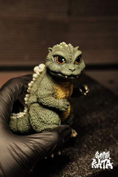 a small toy lizard sitting on top of a black glove