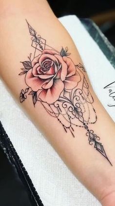 a rose tattoo on the left arm with an arrow and beads around it's center