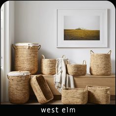 several woven baskets are stacked on top of each other in front of a framed photograph