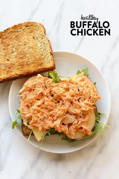 a white plate topped with a sandwich next to a slice of bread