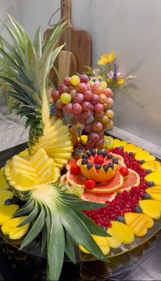 a fruit platter with pineapples, grapes, and oranges