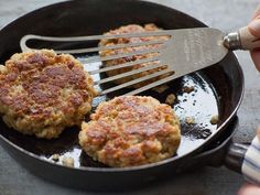 two hamburger patties cooking in a skillet with a spatula being used to stir them