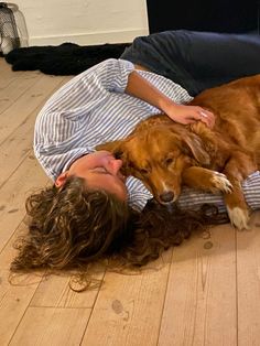 a woman laying on the floor next to a brown dog with its head on her owner's chest