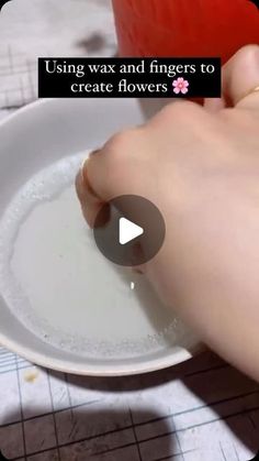 a person is dipping something into a bowl with water in it and the words using wax and fingers to create flowers