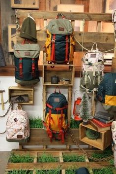 several backpacks are on display in a room filled with wood pallets and grass