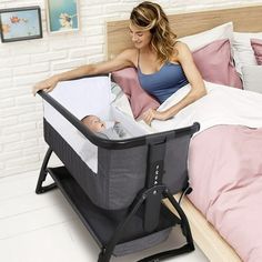 a woman laying in bed next to a baby crib