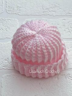 a pink knitted hat sitting on top of a white brick wall