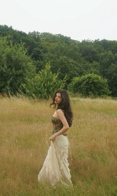 a woman in a dress is standing in the grass