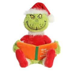 the grinch is reading a book while wearing a santa hat and holding it in his hands