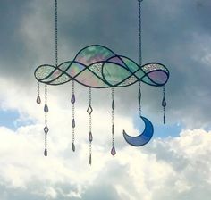 a wind chime hanging from the side of a cloudy sky with crescents and stars