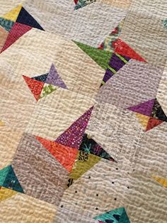 a close up view of a quilt with many different colors and shapes on it,