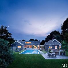 an outdoor dining area next to a swimming pool at dusk with the sun shining on the house