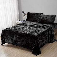 a bed with black velvet sheets and pillows