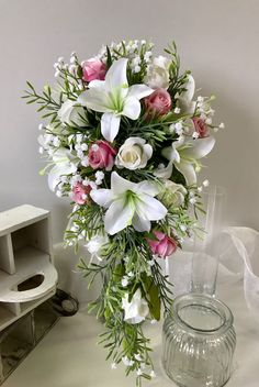 a bouquet of white and pink flowers sitting on a table next to a glass vase