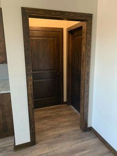 an empty room with two wooden doors and hard wood flooring on the other side