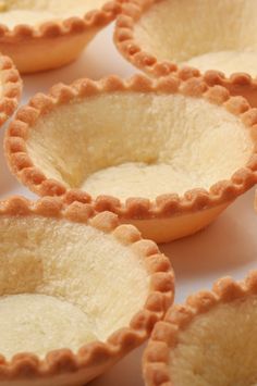 small pies are lined up on a white table top, ready to be eaten