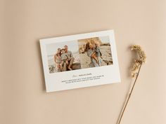 a couple's photo is placed on top of a card next to a dried flower