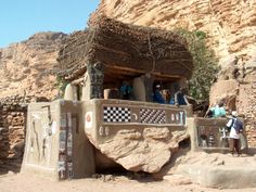 some people are standing in front of an adobe structure with stone walls and painted designs