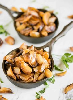 two spoons filled with cooked mushrooms on top of a table