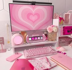 a desk with a computer, keyboard and pink accessories