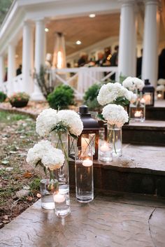 white flowers are in vases on the steps leading up to an outdoor wedding venue