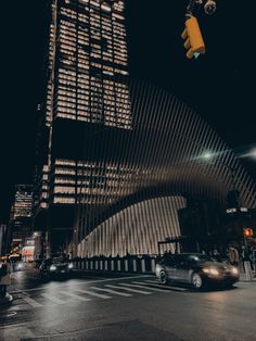 a car is driving down the street in front of a tall building with many windows