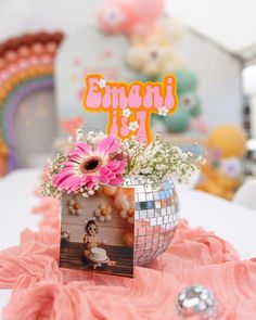 a table with a disco ball centerpiece and pink flowers