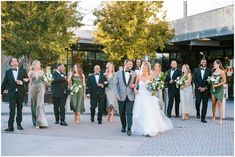 a bride and groom walking with their bridal party in front of the building at sunset