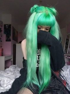 a woman with green hair sitting on top of a bed