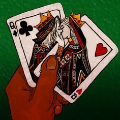 a hand holding two playing cards in front of a green background with the queen and king of spades