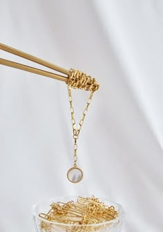 a bowl filled with lots of gold colored metal items on top of a white surface