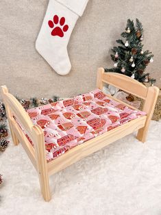 a small wooden bed with pink and red bedspread next to a christmas tree