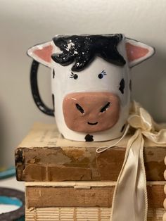 a cow mug sitting on top of a stack of books with a ribbon tied around it